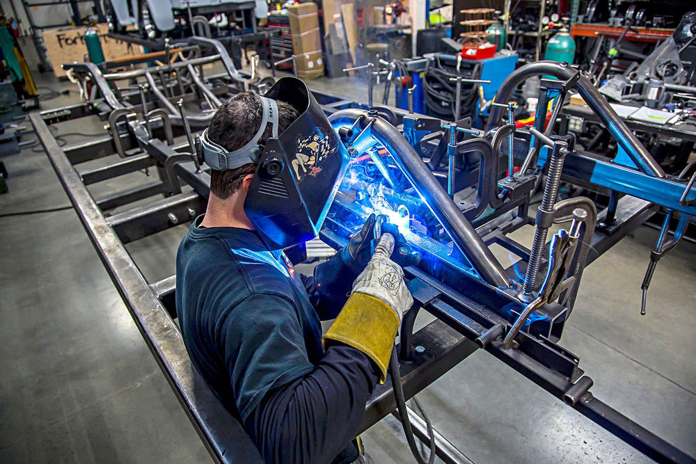 Skilled fabricator welding a custom performance chassis at Hot Rod Town Garage's Builders & Craftsmanship experience.
